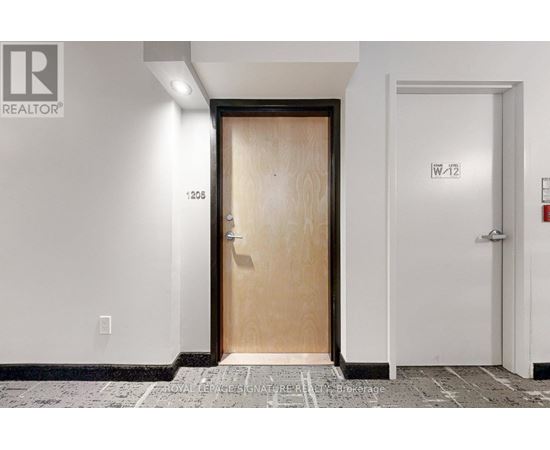 A white hallway with a wooden door and a white door on the right.