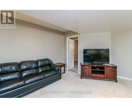 A black leather couch sits in a living room with a wooden entertainment center and a flat screen TV.