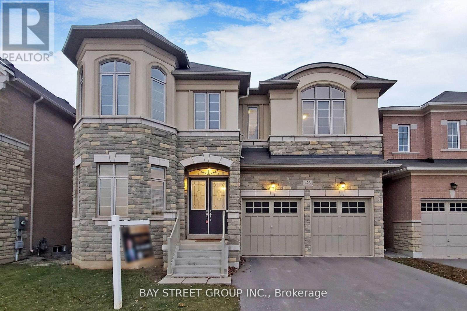 A large house with a stone facade and a bay window is for sale.