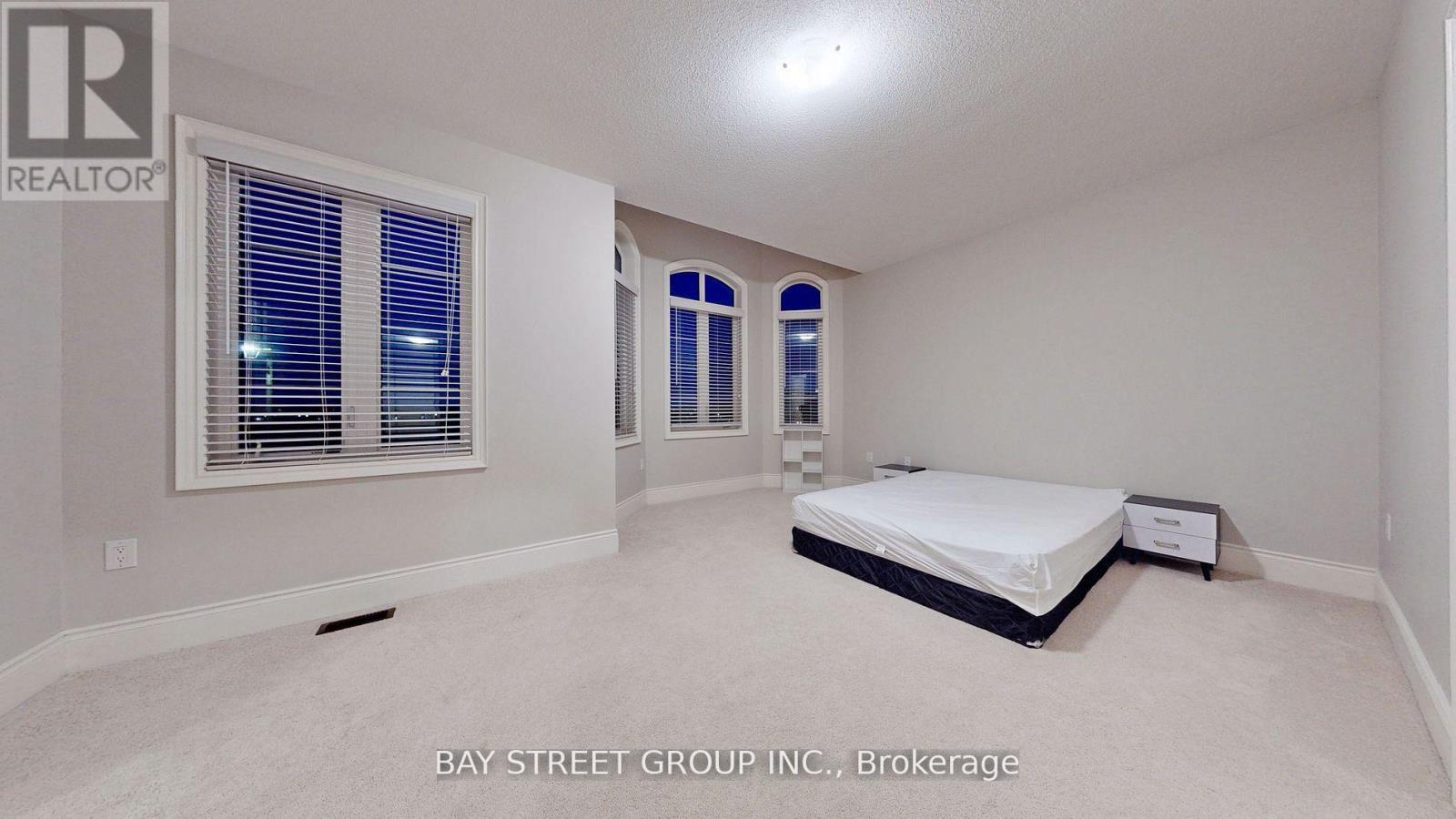 A bedroom with a bed, a window with blinds, and a sign that says "REALTOR".