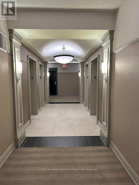 A hallway with a light fixture hanging from the ceiling and doors on both sides.