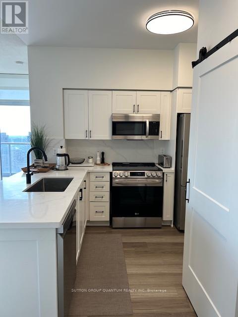 A modern kitchen with white cabinets and stainless steel appliances.