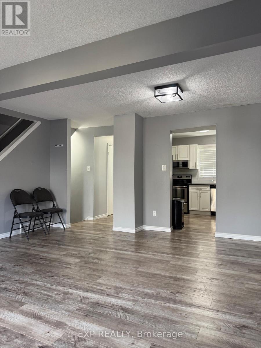 A room with a wooden floor and a kitchen in the background.