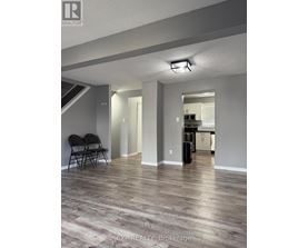 A room with a wooden floor and a kitchen in the background.