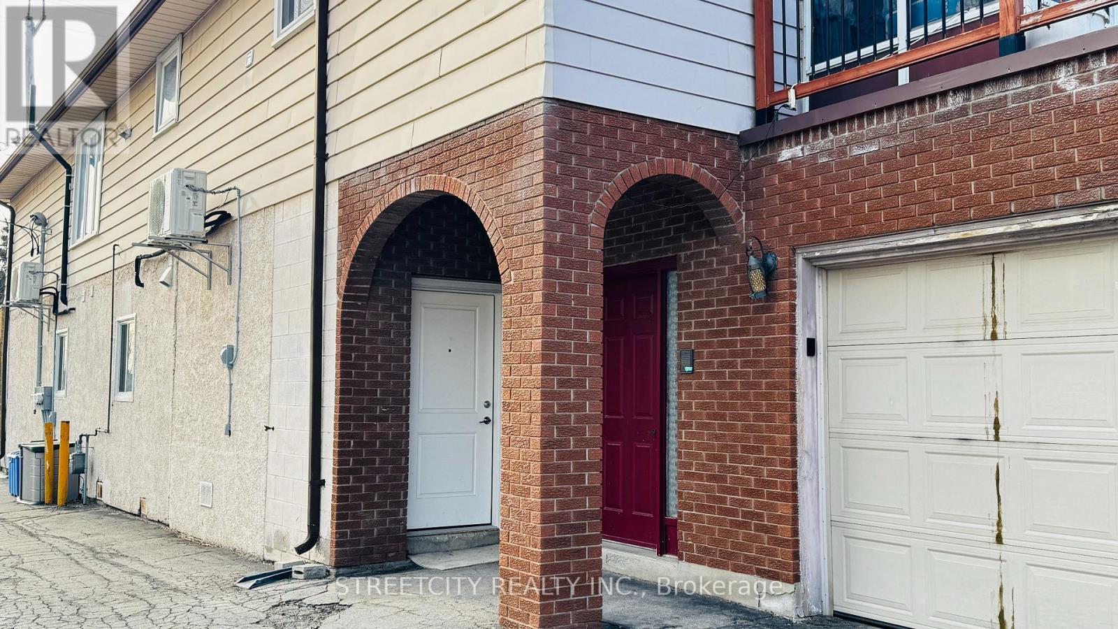 A red door is on the left side of a white garage door.