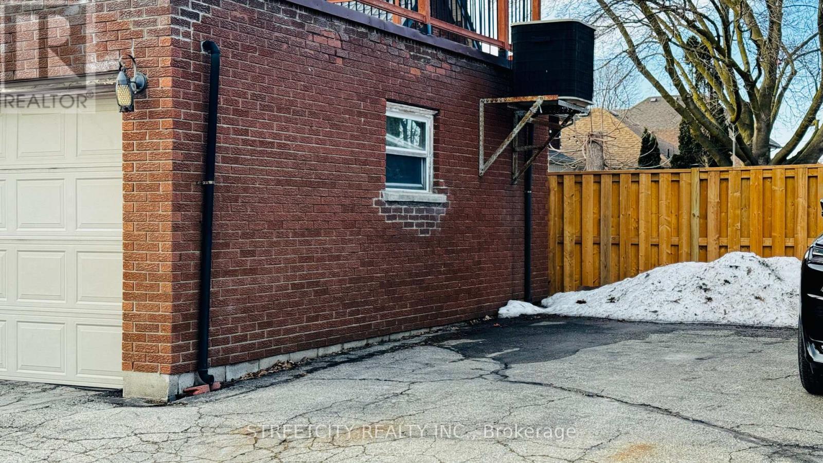 A brick building with a white garage door and a black pipe.