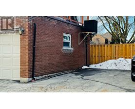 A brick building with a white garage door and a black pipe.