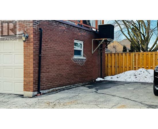 A brick building with a white garage door and a black pipe.