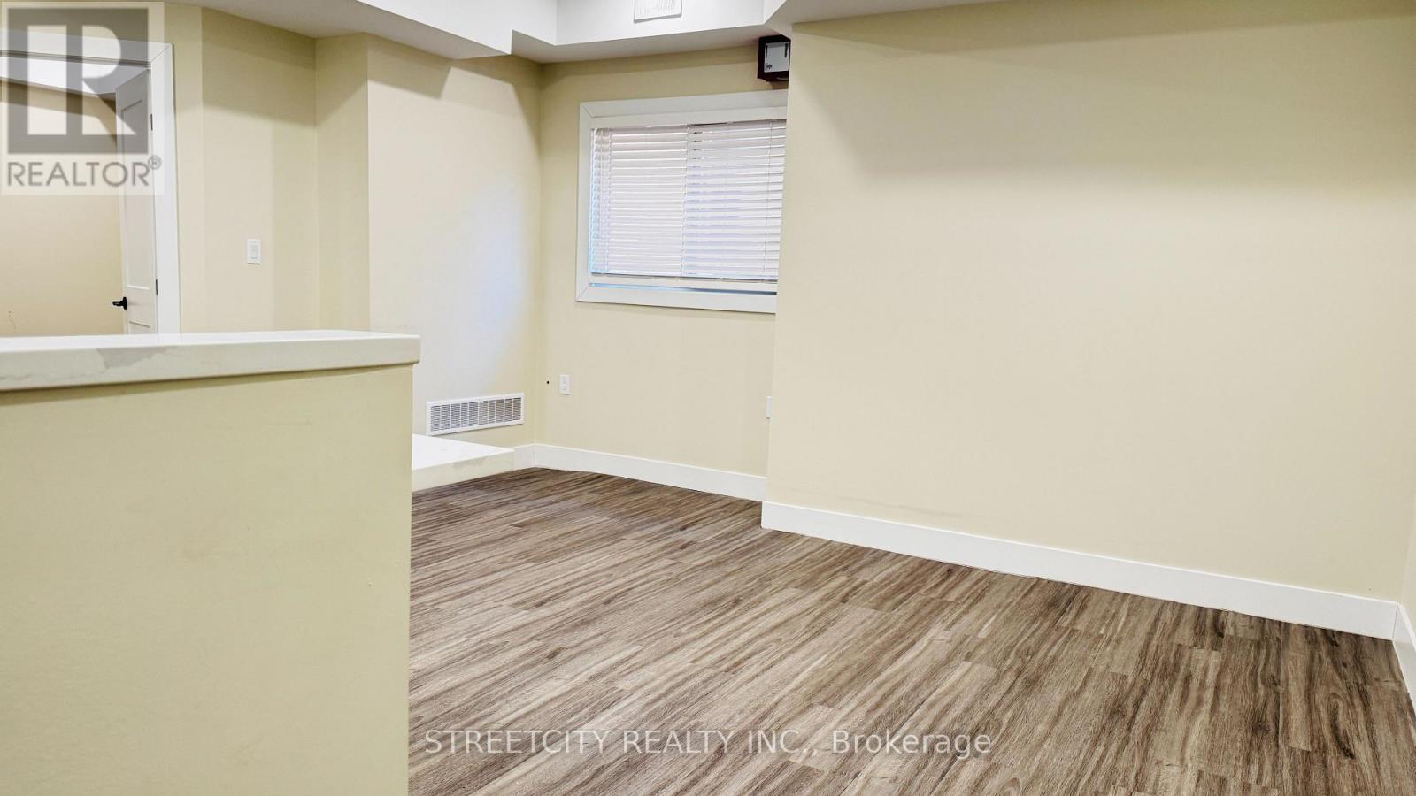 A room with a wooden floor and a window with blinds.
