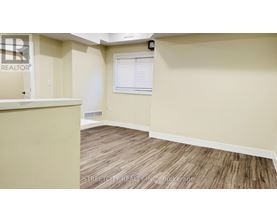 A room with a wooden floor and a window with blinds.