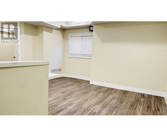 A room with a wooden floor and a window with blinds.