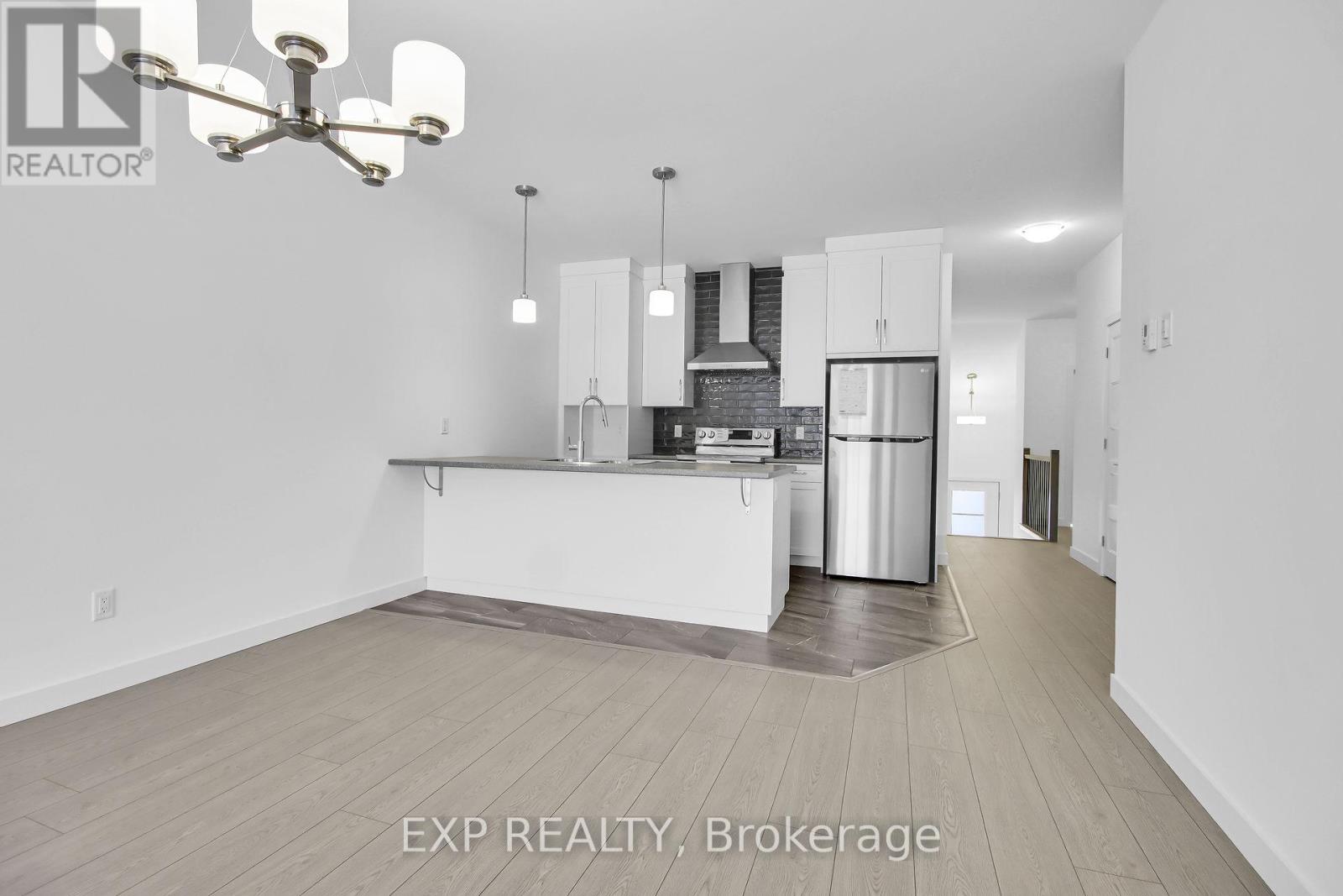 A modern kitchen with white cabinets and a stainless steel refrigerator.