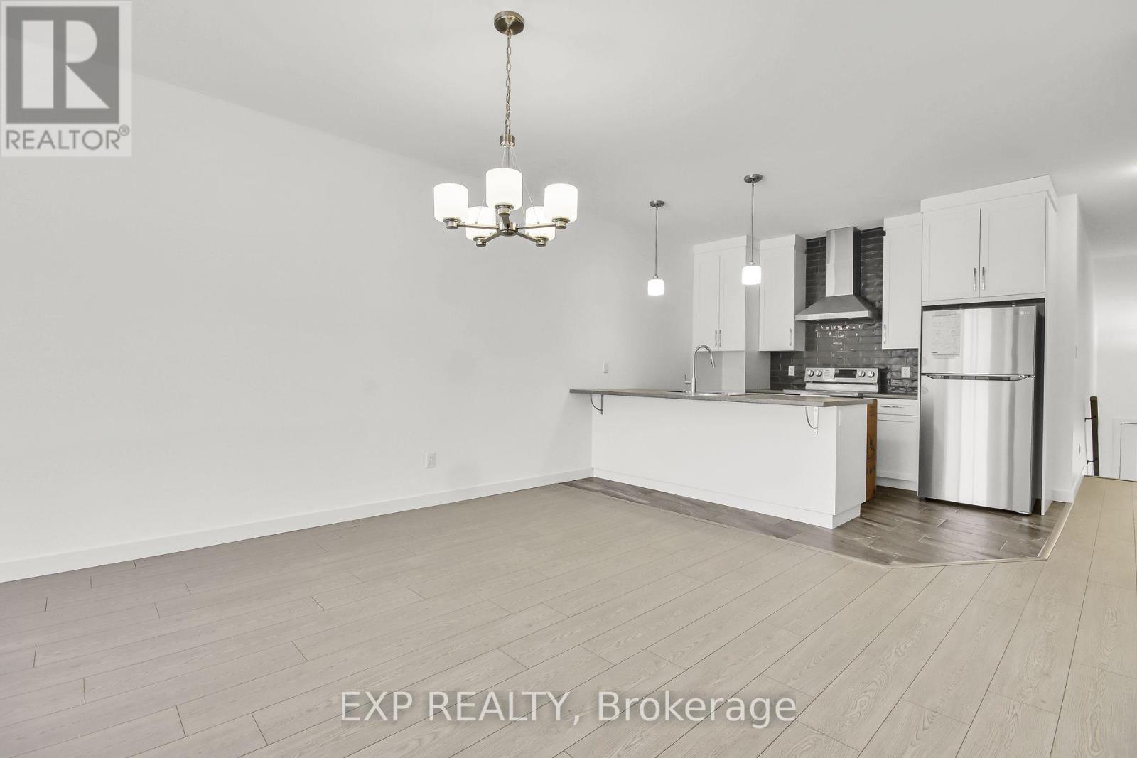 A black and white photo of a kitchen with a chandelier hanging from the ceiling.