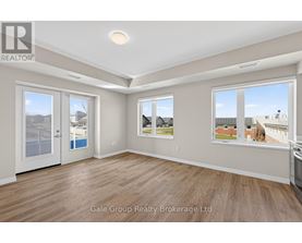 A spacious room with wooden flooring and large windows showing a view of other buildings.