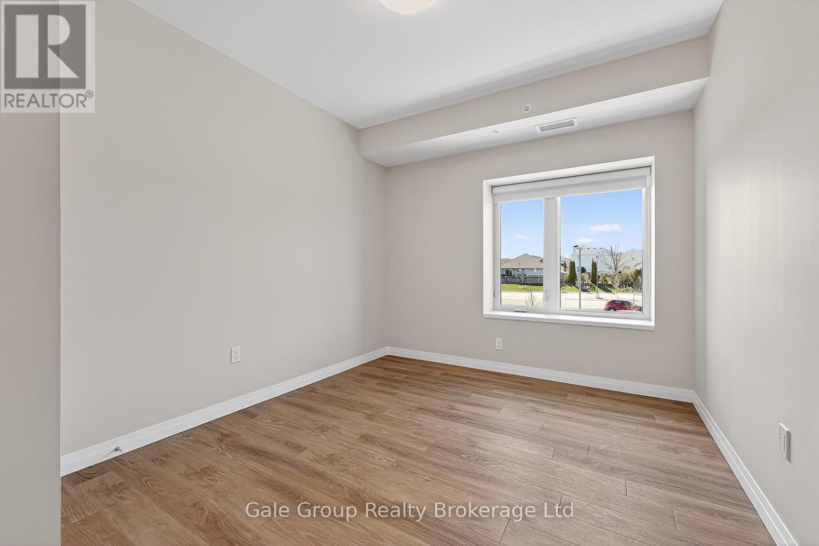 A room with a window showing a view of houses and trees outside.