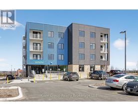 A modern two-story building with a blue and gray facade and a parking lot in front.