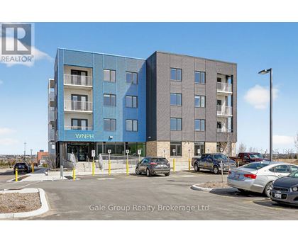 A modern two-story building with a blue and gray facade and a parking lot in front.