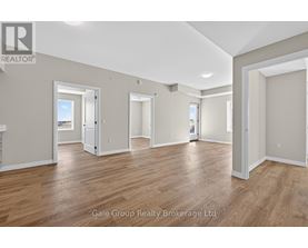 A spacious room with wooden flooring and white walls, part of a real estate brokerage.