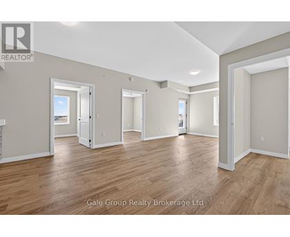 A spacious room with wooden flooring and white walls, part of a real estate brokerage.