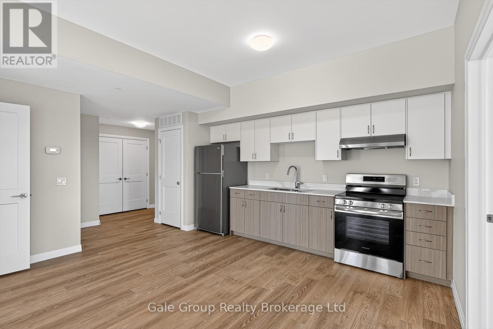 A kitchen with white cabinets and a stainless steel refrigerator.