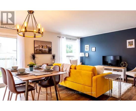 A living room with a yellow couch and a dining table with chairs.