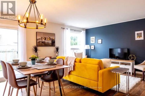 A living room with a yellow couch and a dining table with chairs.