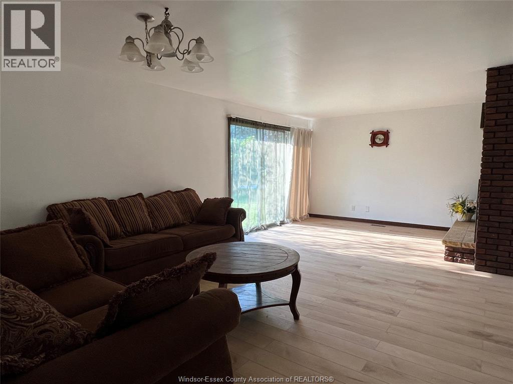 A living room with a brown couch and a chandelier.
