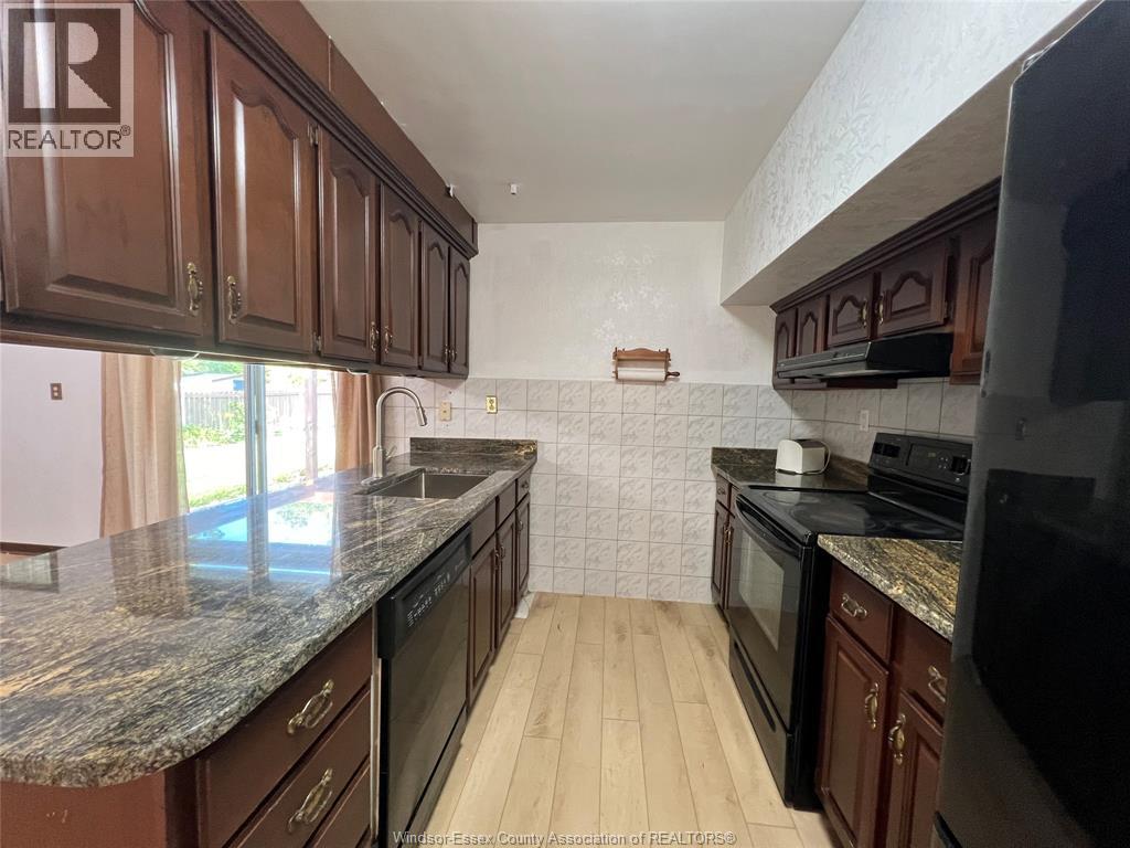 A kitchen with brown cabinets and black appliances.