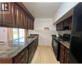 A kitchen with brown cabinets and black appliances.