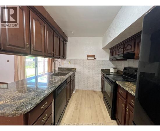 A kitchen with brown cabinets and black appliances.