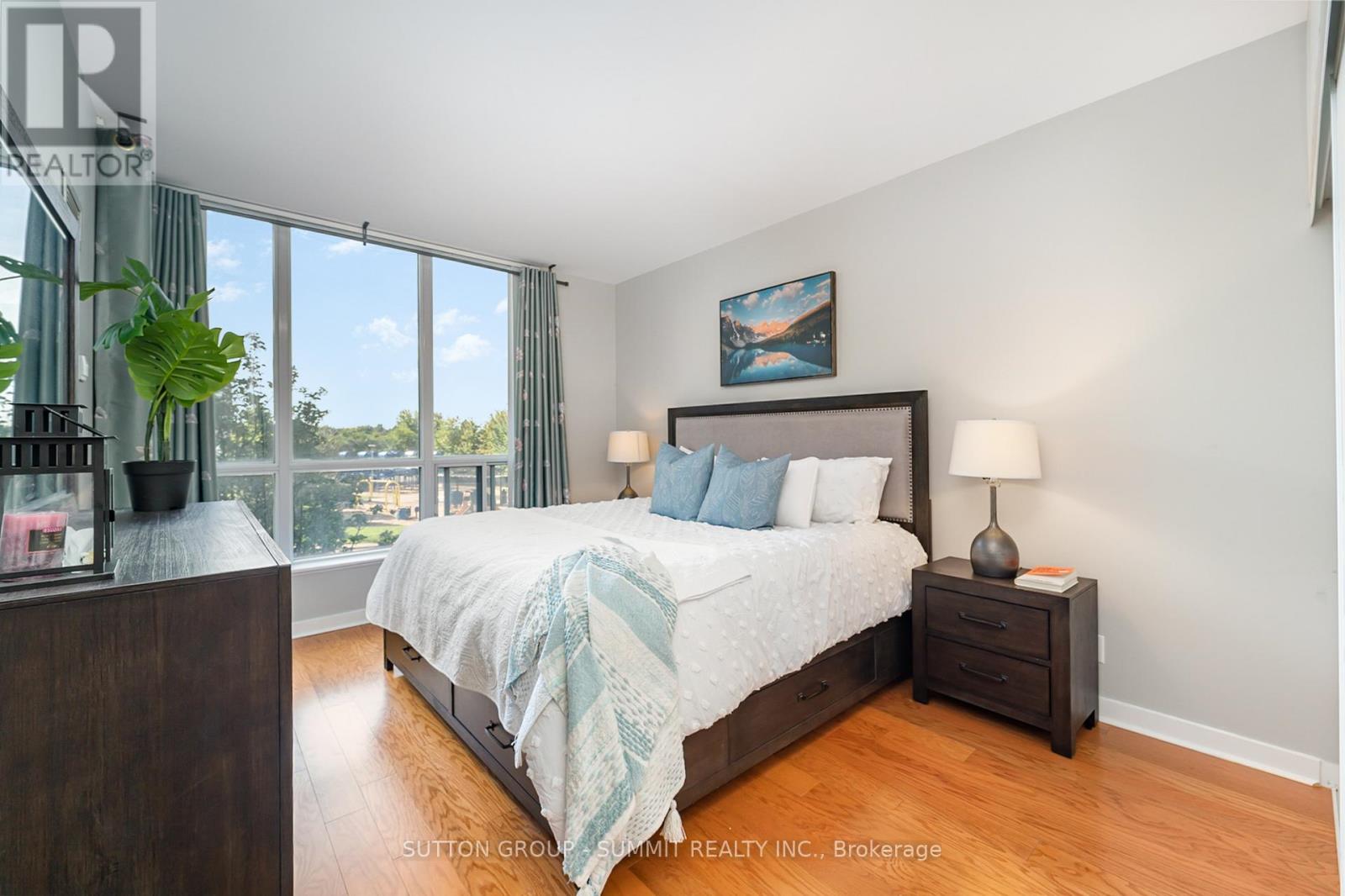A bedroom with a large bed and a view of the trees outside the window.