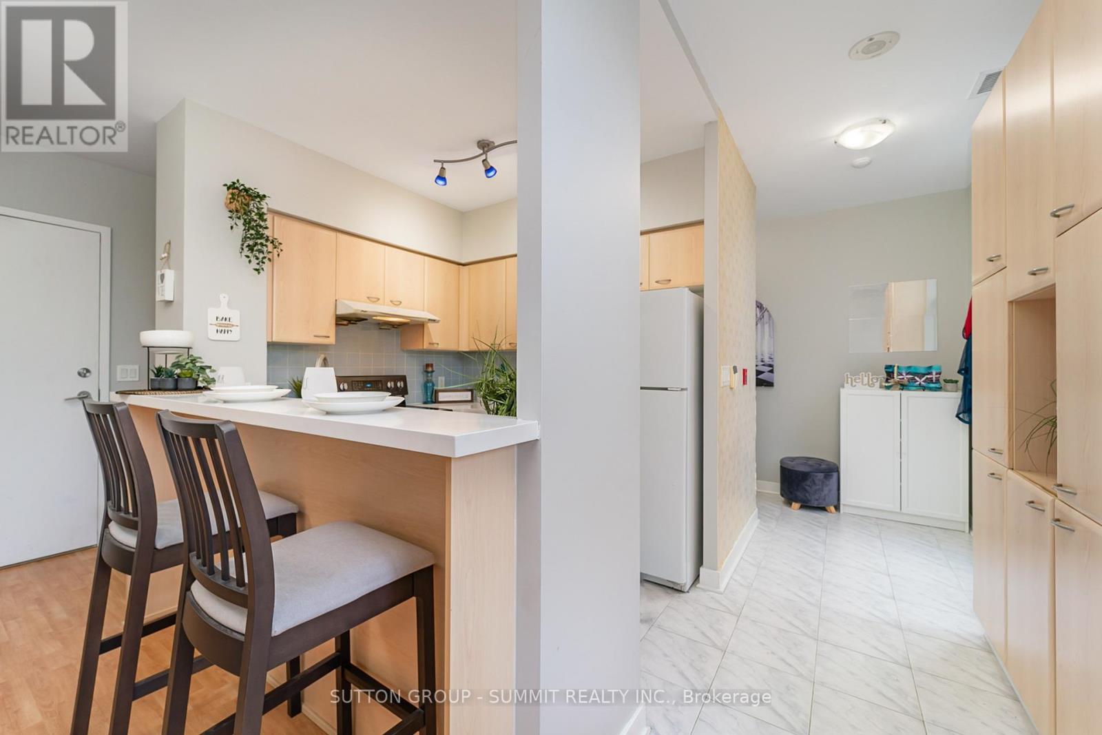 A kitchen with a desk and chairs in front of it.