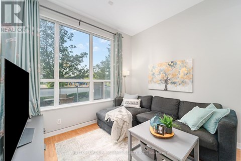 A living room with a grey couch, a coffee table, and a painting on the wall.