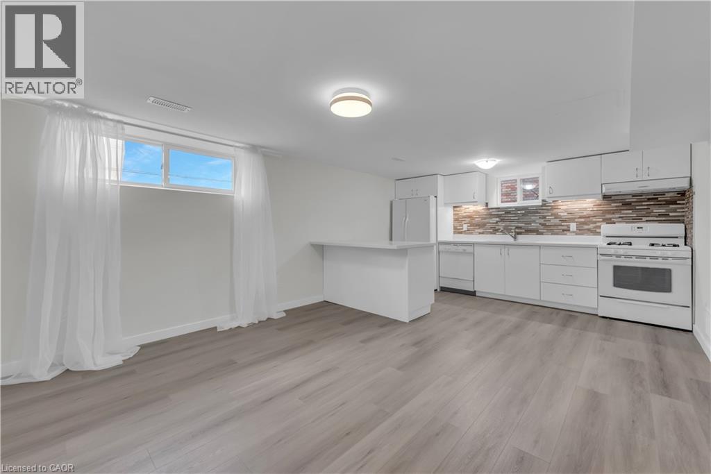 A well-lit, spacious kitchen with white cabinets and a wooden floor.