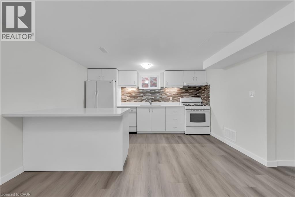 A modern kitchen with white cabinets and a wooden floor.