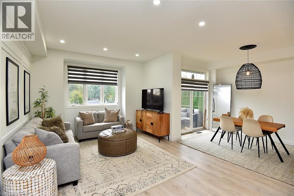 A living room with a grey couch, a brown ottoman, a wooden cabinet, a television, and a dining table with chairs.