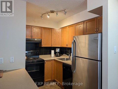A kitchen with wooden cabinets and a stainless steel refrigerator.