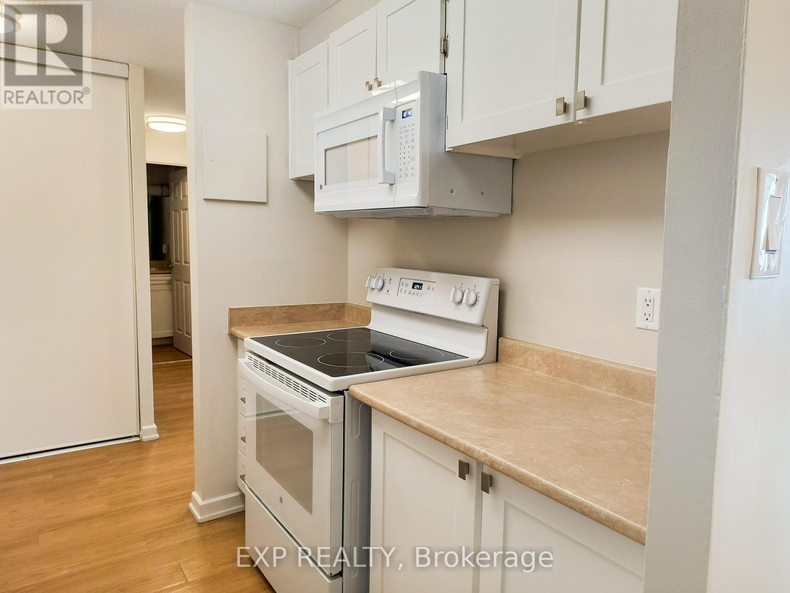 A kitchen with white cabinets and a stove top oven.