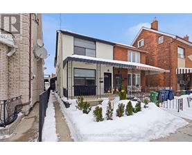 A snow-covered sidewalk leads to a modern building with a glass entrance.