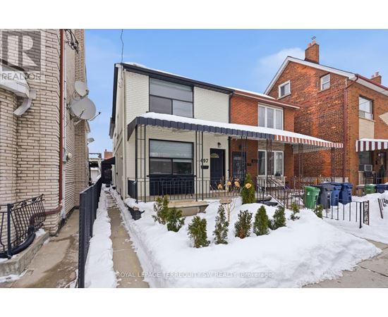 A snow-covered sidewalk leads to a modern building with a glass entrance.
