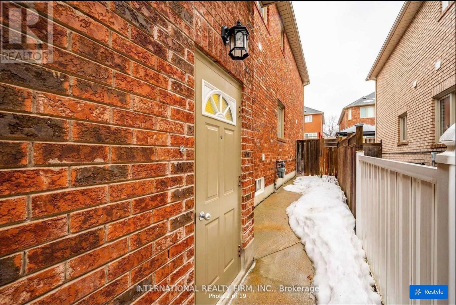 A red brick wall with a white door and a black lantern above it.