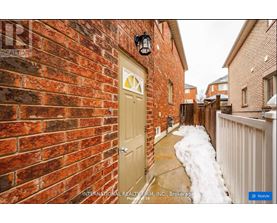 A red brick wall with a white door and a black lantern above it.