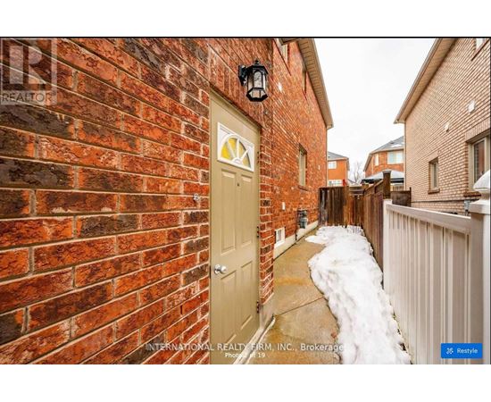 A red brick wall with a white door and a black lantern above it.