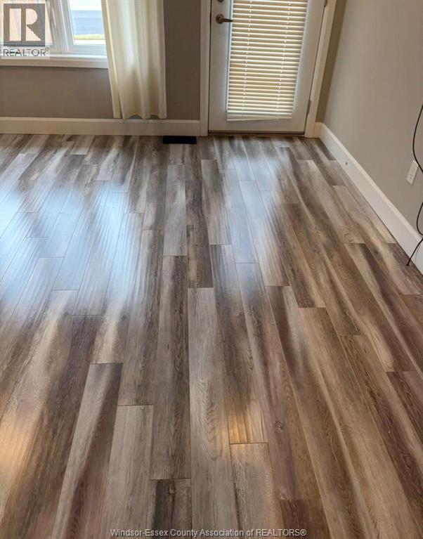 A room with a wooden floor and a door with blinds.