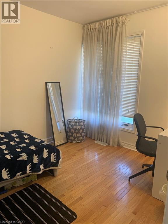 A bedroom with a bed, chair, and window with curtains.