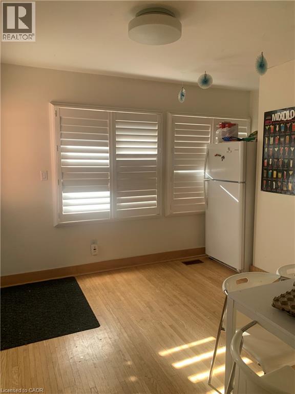 A kitchen with a white fridge and wooden floors.