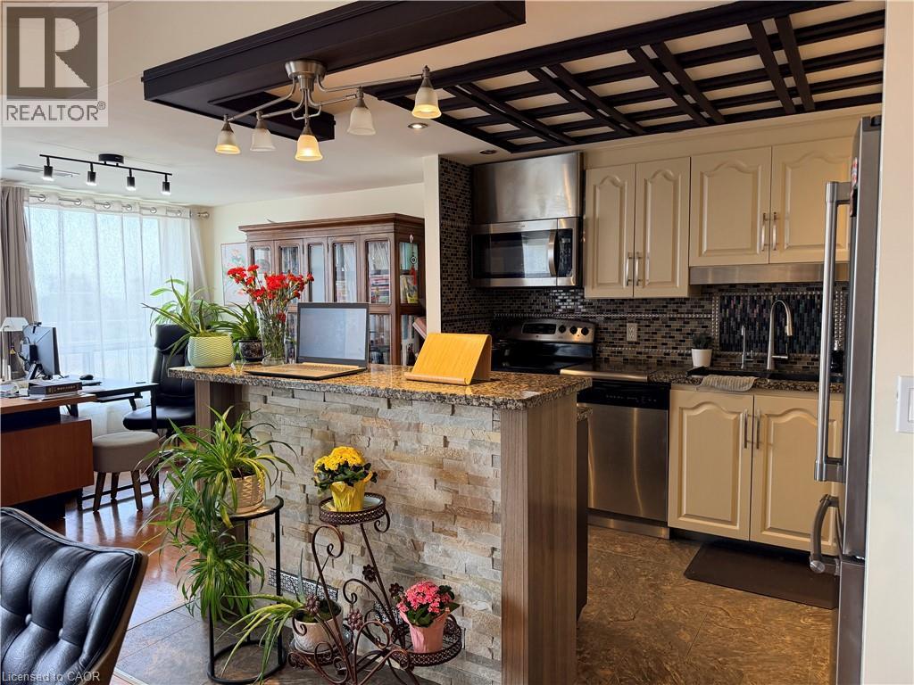 A kitchen with a stone counter and a stainless steel refrigerator.