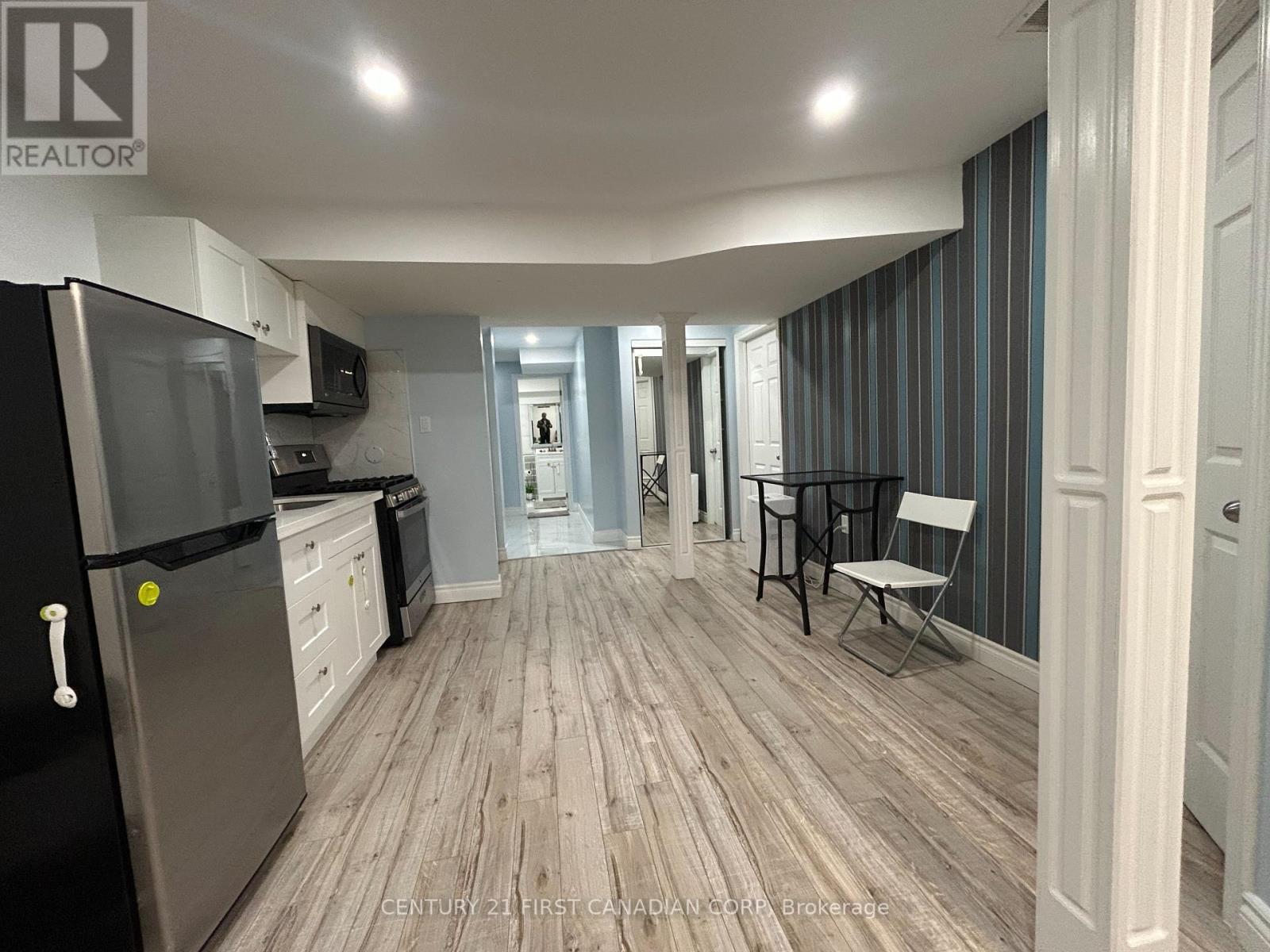 A kitchen with a refrigerator, a dining table and chairs, and a hallway.