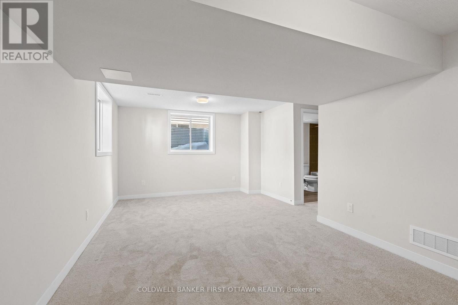 A spacious, empty room with a window and carpeted floor.
