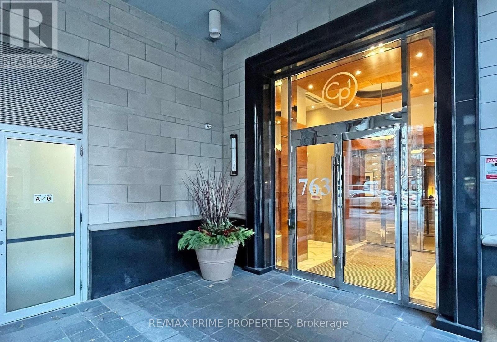 The entrance to a building with a glass door and a plant in front.